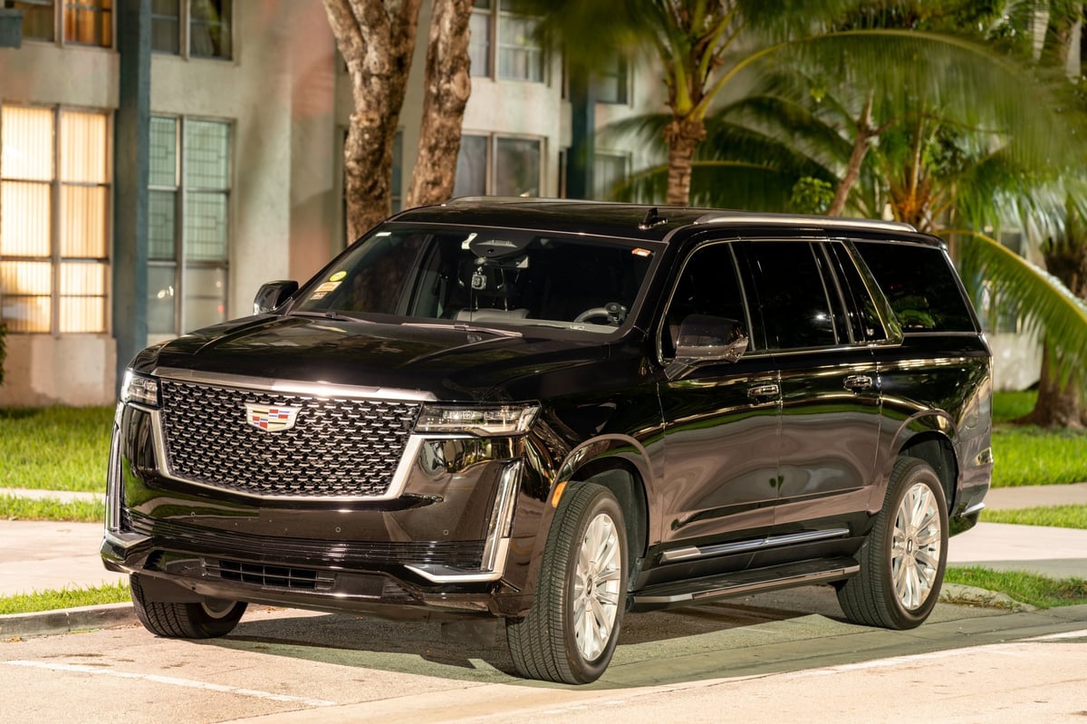 Luxury Cadillac Escalade SUV limo at night with city lights