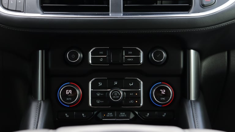 Vehicle dashboard climate control panel with dual temperature displays, central controls, and air vents