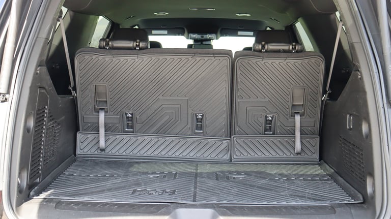 Empty vehicle cargo trunk with folded rear seats and protective mat lining the floor
