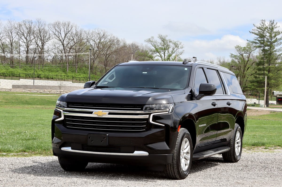 Black Chevrolet Tahoe SUV parked on driveway with trees and green grass in background