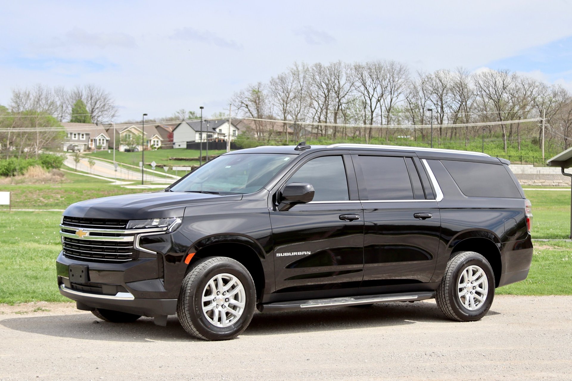 Black Chevrolet Suburban SUV parked in a driveway with suburban homes and trees visible in the background