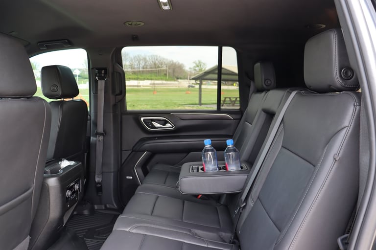 Interior of a truck cabin with gray leather seats, center console with water bottles, and rural landscape visible through windows