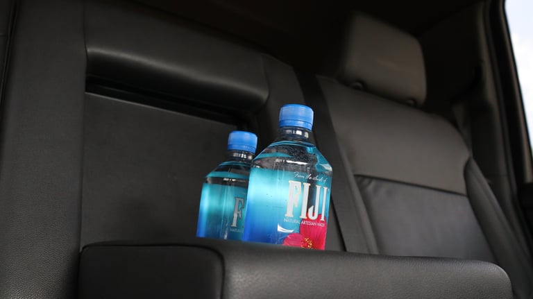 Two plastic water bottles with blue caps sitting on a car seat